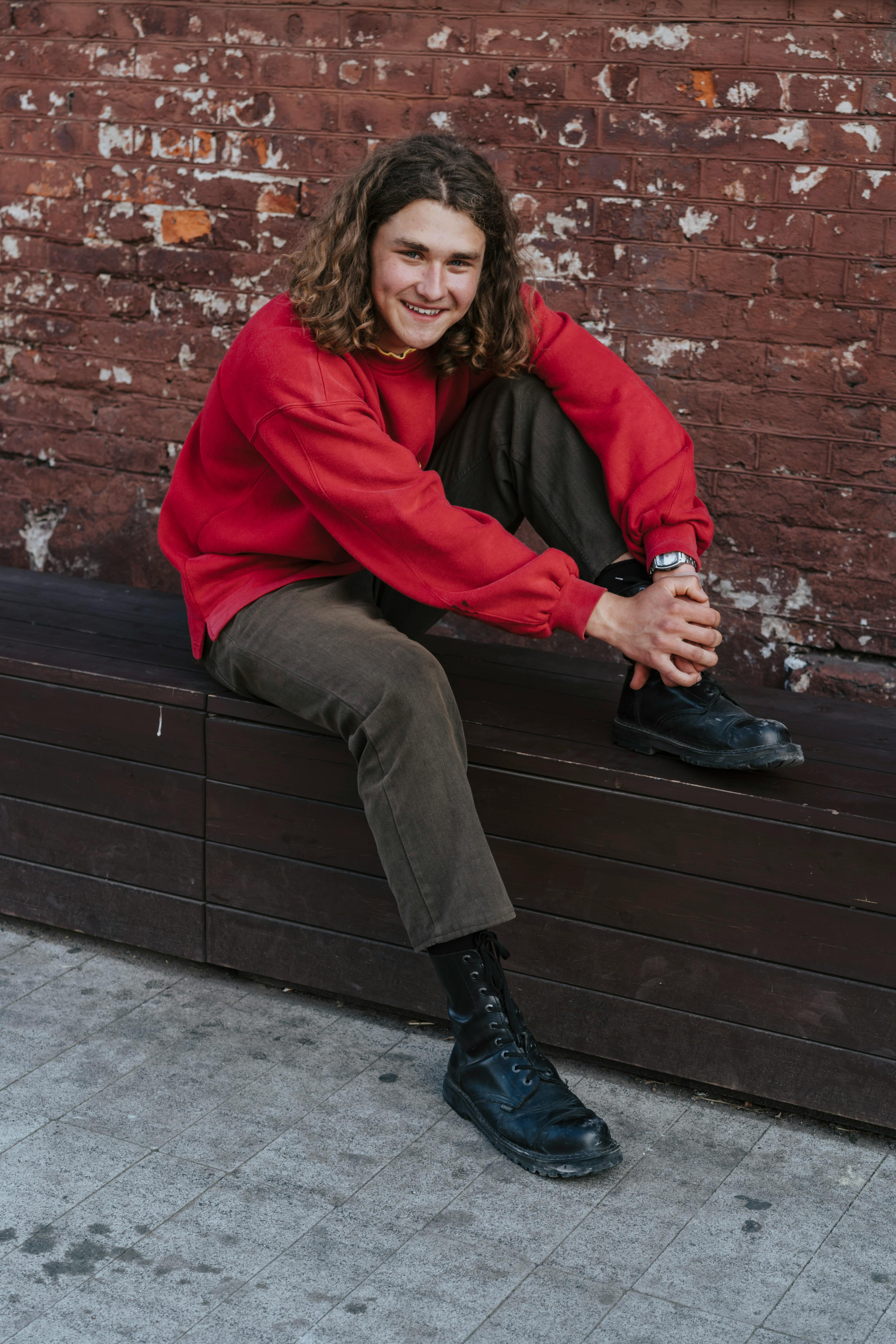 Casual portrait of a young man in a red sweater against a brick wall in Minsk, Belarus.