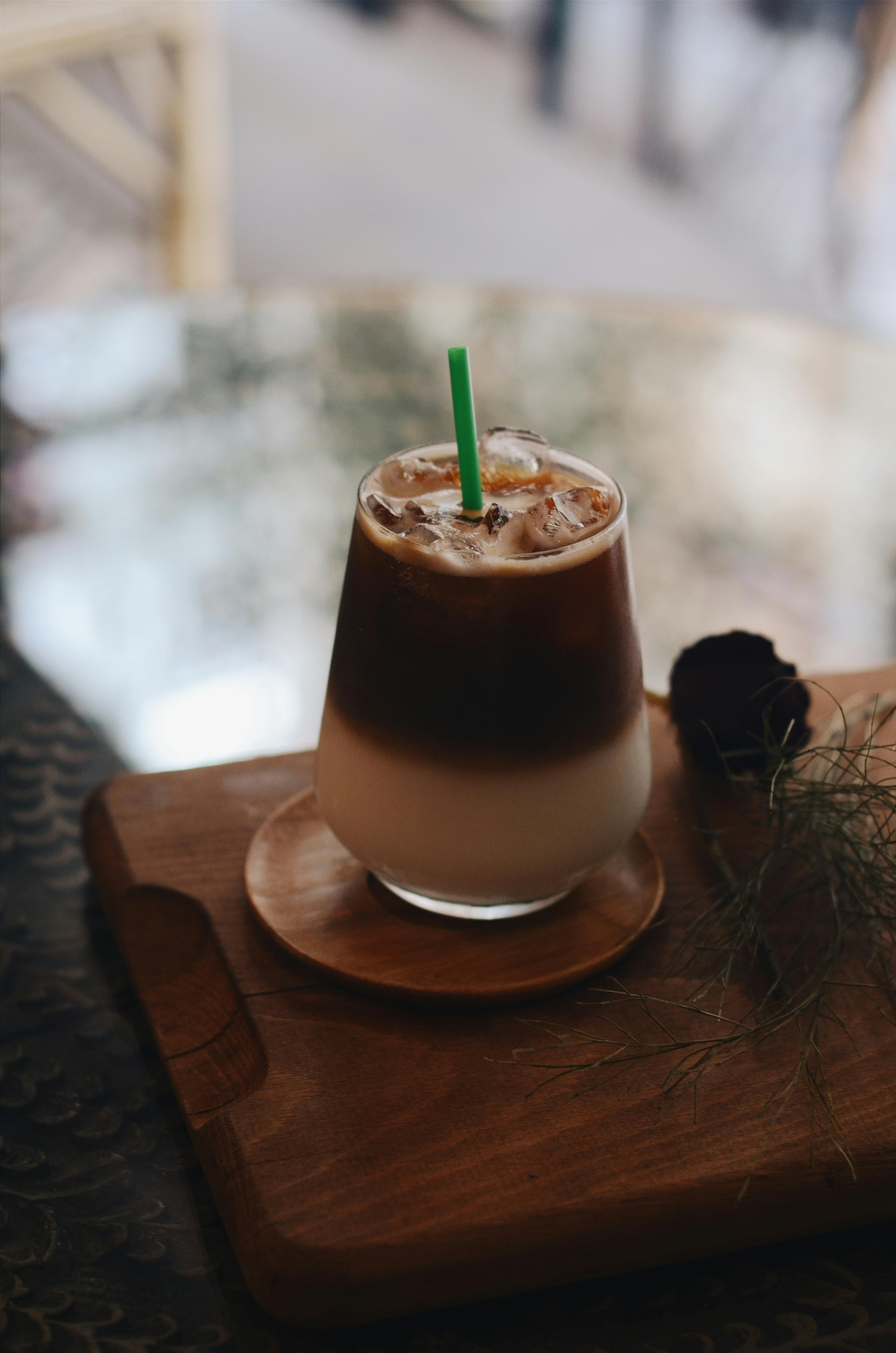 A creamy iced coffee served with a straw on a wooden tray, capturing a cozy cafe ambiance.
