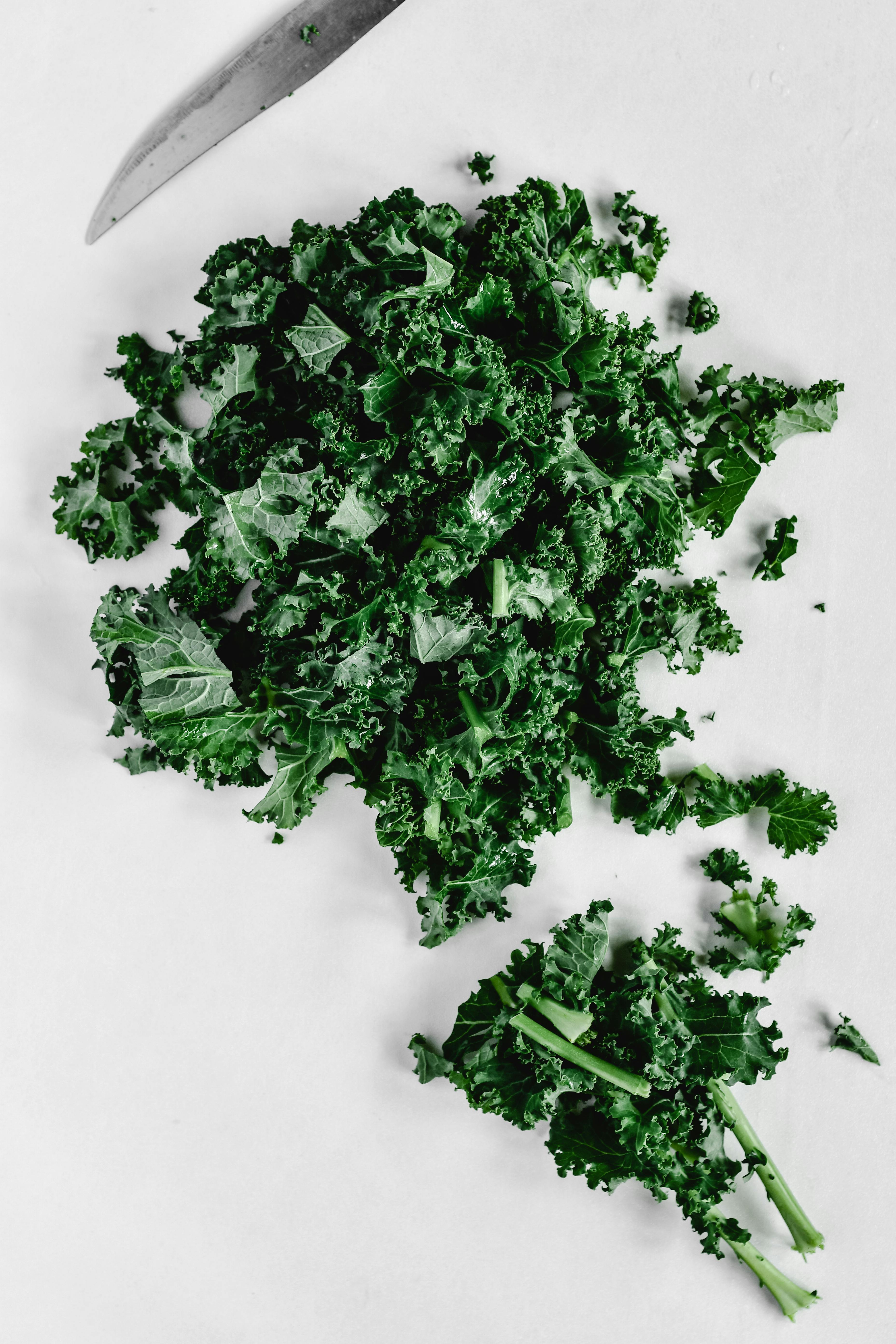 Freshly chopped kale on a white surface, ideal for healthy food prep concepts.